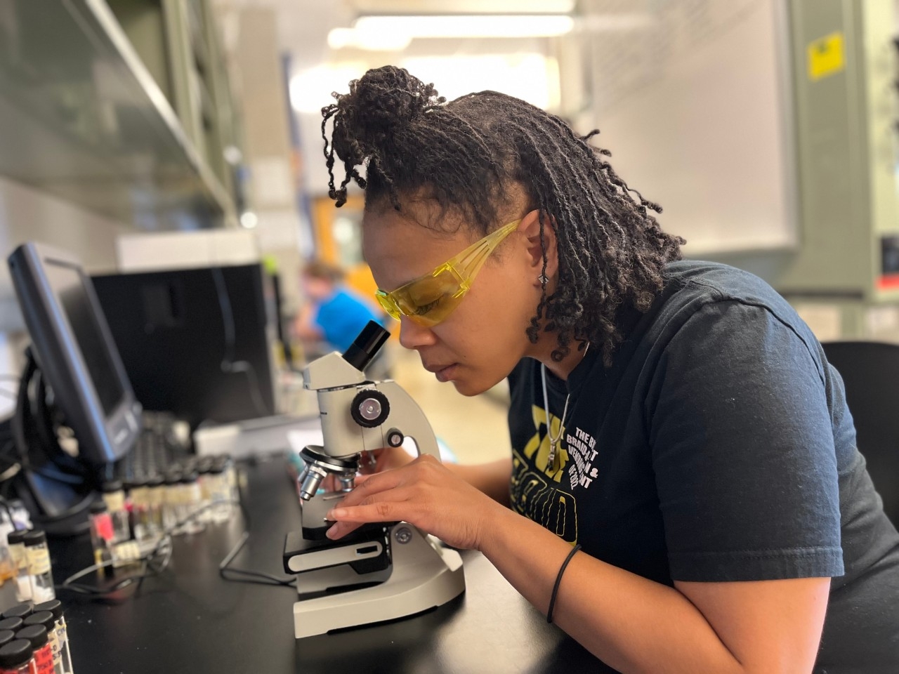 NKU Chemistry major looks into a microscope and records data.