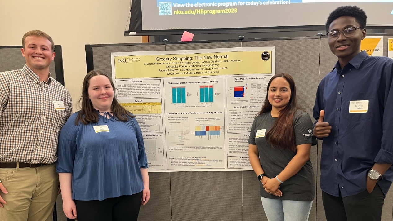 Research students smile in front of their research poster at a research celebration event.