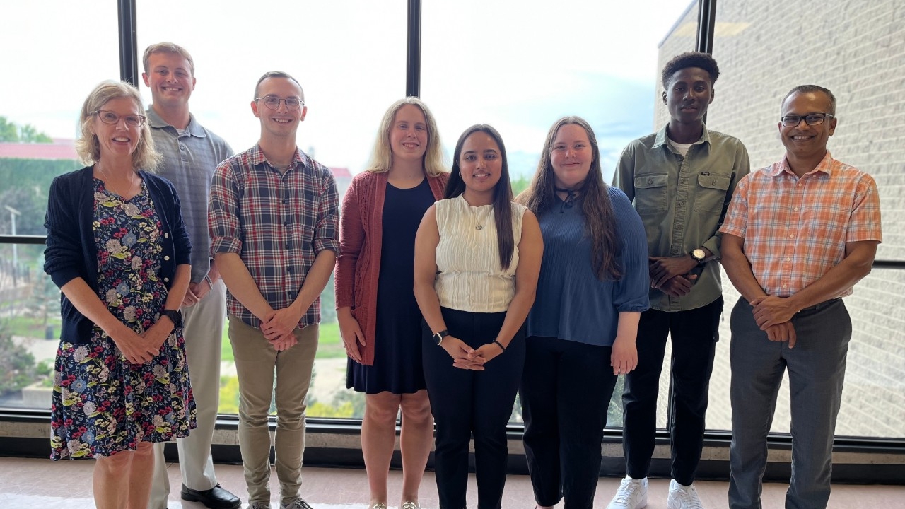 NKU undergraduate students pose for a picture with faculty and a community partner after a successful research presentation.