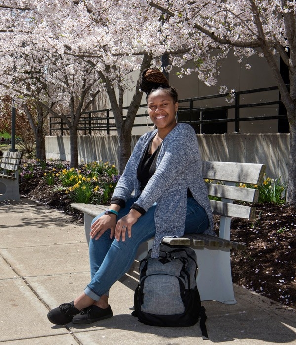 Student smiling sitting on a bench.